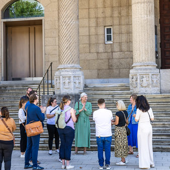 Stadtgäste während einer Führung stehen vor dem Museum