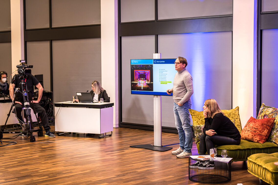 Ein Referent hält die Rede und zeigt eine Präsentation auf dem Bildschirm