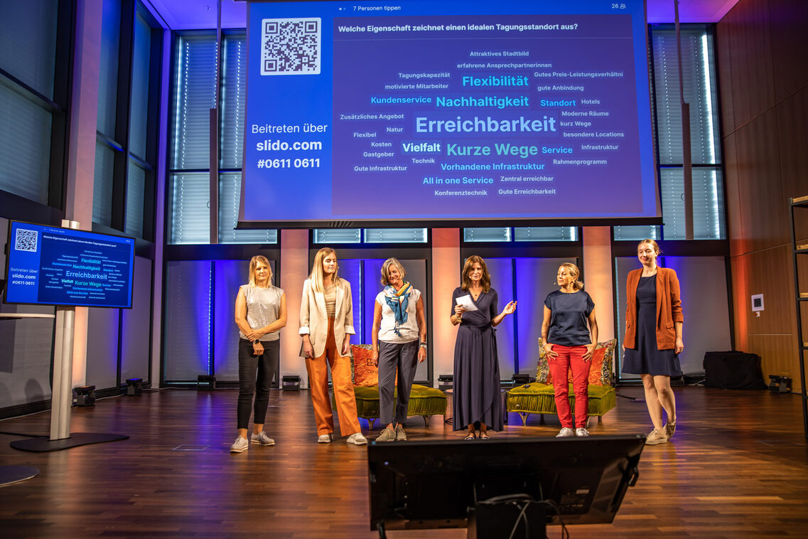 Sechs Frauen stehen vor einem Bildschirm