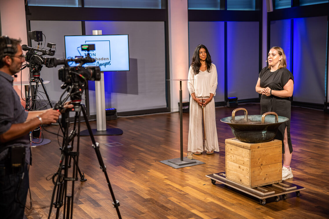 Eine Frau im schwarzen Kleid gibt einen Vortrag