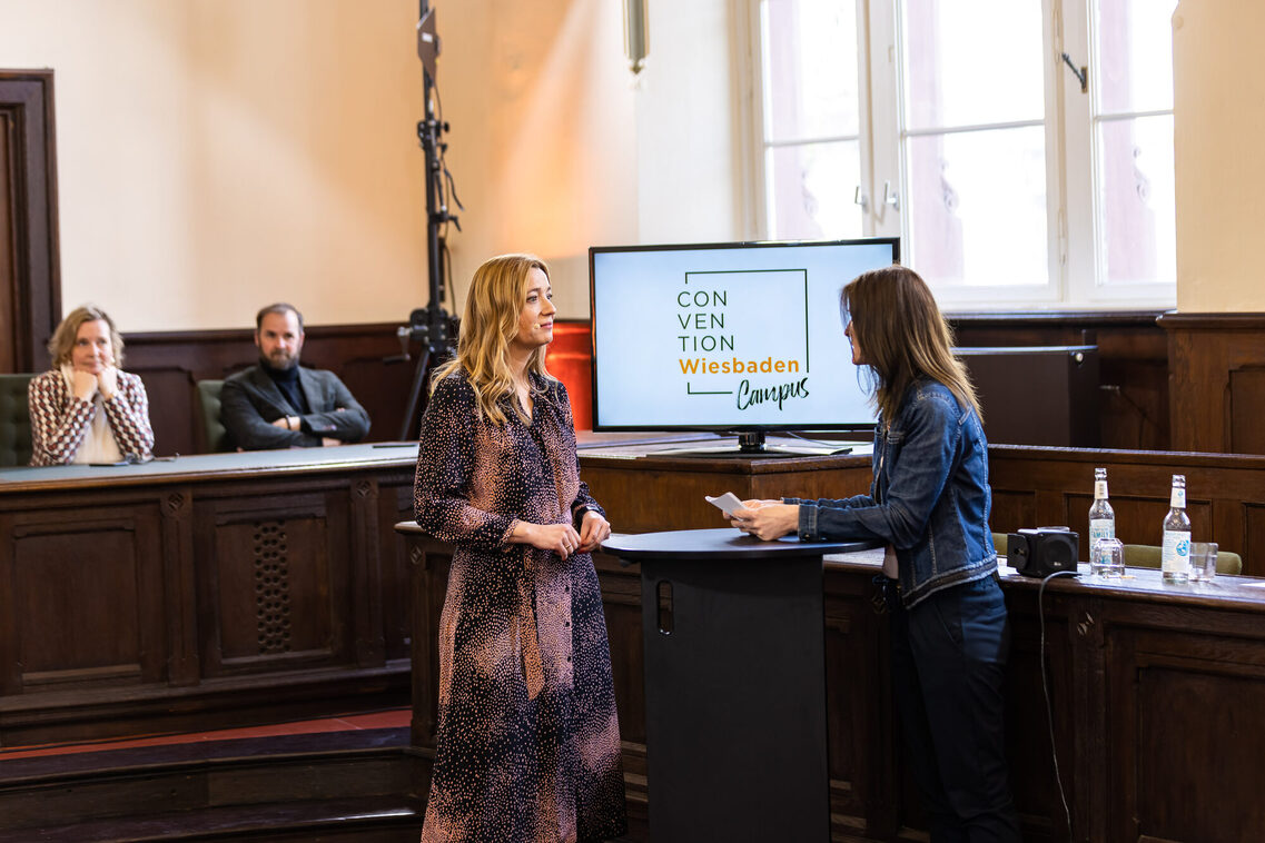 Eine Frauen stehen am Tisch vor dem Bildschirm