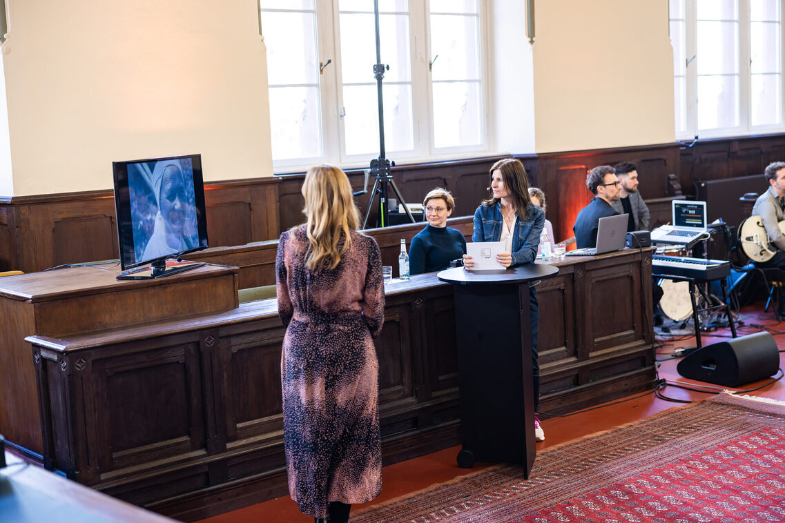 Zwei Frauen stehen und schauen sich das Video am Bildschirm an