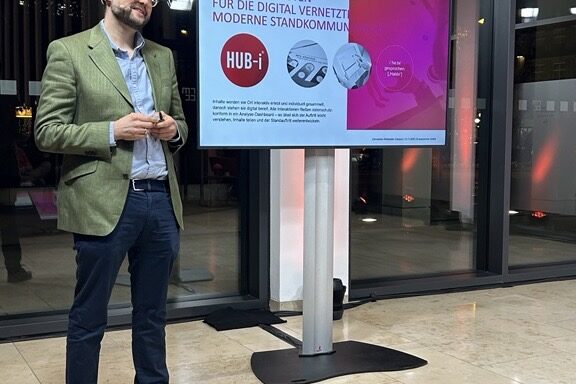 Mann beim präsentieren neben Bildschirm