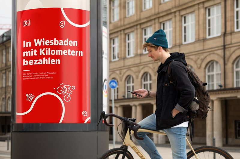 Radfahrer vor dem Museum Wiesbaden mit Werbung für die Fahrrad App DB Rad+