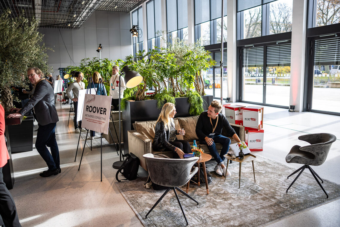 Menschen sitzen auf dem Sofa in der Messehalle und unterhalten sich