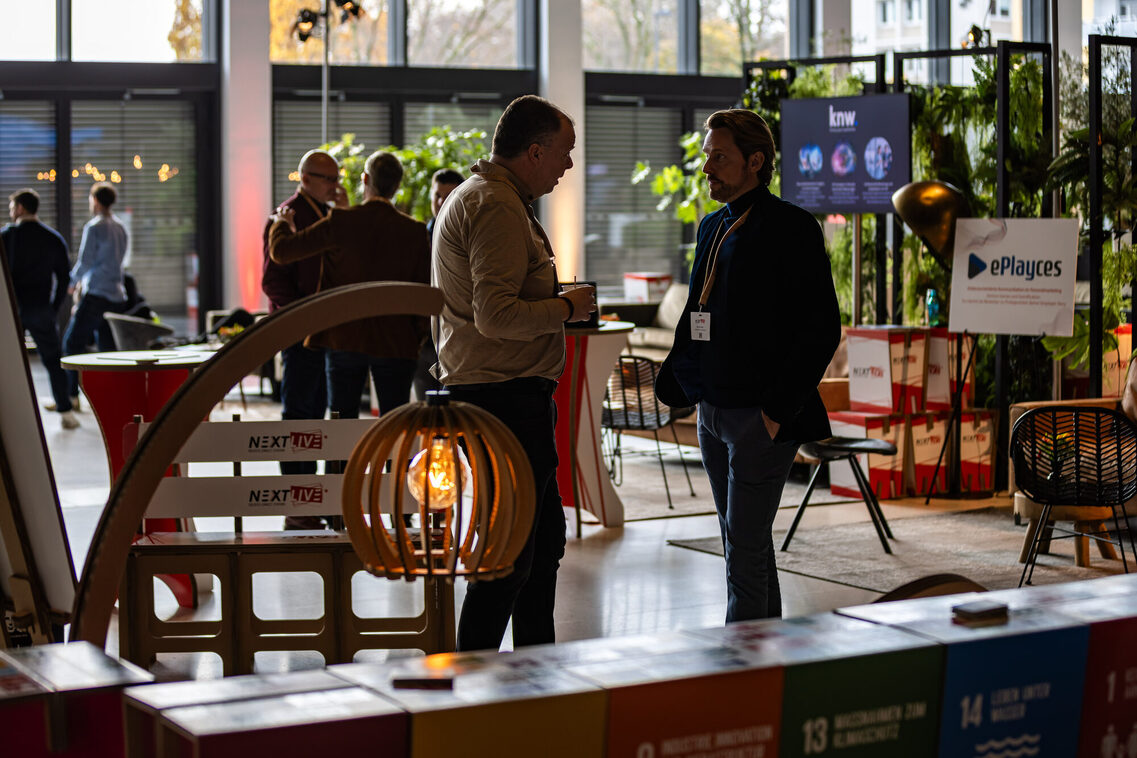 Menschen stehen in der Messehalle und unterhalten sich
