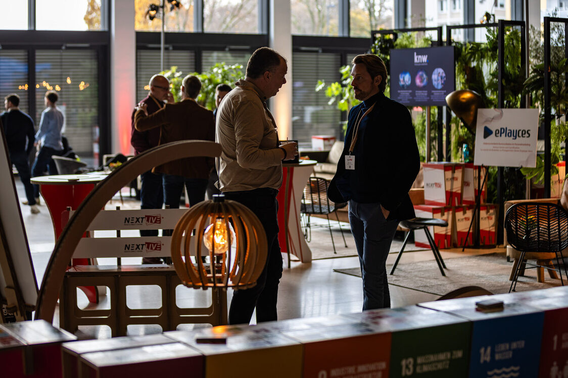 Menschen stehen in der Messehalle und unterhalten sich