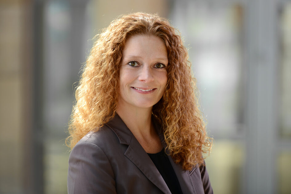 Porträtfoto Alexa Ickert lächelnd mit offenenen langen lockigen Haaren in Blazer