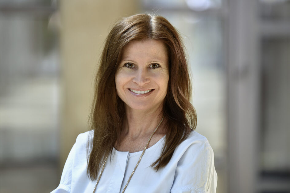 Porträtfoto Ulrike Theis lächelnd mit offenen langen Haaren mit langer Kette in Bluse.
