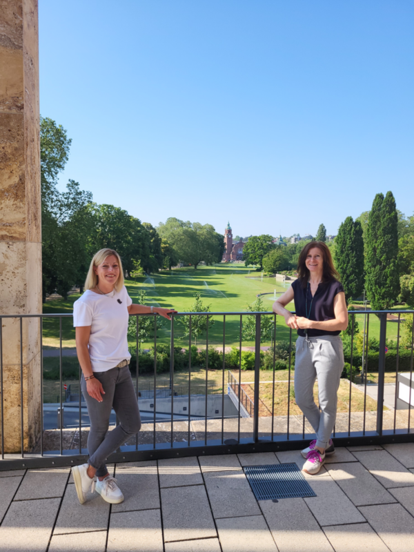 Zwei Frauen auf einer Terasse im RMCC mit Blick auf die Grünanlagen und Hauptbahnhof